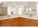 Bathroom vanity with double sinks, wood cabinets, large mirror, and bright lighting at 9836 Old Patina Way, Orlando, FL 32832
