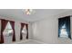 A room with grey walls and two windows with burgundy-red curtains, plus overhead lighting at 10249 Spring Lake Dr, Clermont, FL 34711