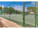 Tennis court with a green chain link fence surrounding it, including a locked gate for security at 10249 Spring Lake Dr, Clermont, FL 34711