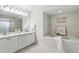 Bright bathroom featuring double sinks, a large mirror, and a separate soaking tub at 10664 Spring Buck Trl, Orlando, FL 32825