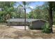 Back of the home with brick patio, lush landscaping, and mature trees at 1090 Braddock Rd, Deltona, FL 32725
