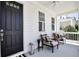 Inviting front porch with neutral chairs, a black door, and views of the serene neighborhood at 1101 Rush Ct, Celebration, FL 34747