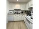 Bright kitchen featuring white cabinets, appliances, and wood-look floors at 1101 Rush Ct, Celebration, FL 34747