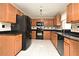 Kitchen features wooden cabinets, black appliances, granite counter tops and tile backsplash at 115 Bristol Forest Trl, Sanford, FL 32771
