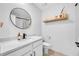 Modern bathroom with a round mirror, shelf decor, and black hardware complementing the vanity and sink at 11574 Buoy Point Pl, Orlando, FL 32832