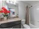 Bright bathroom features a granite vanity with red floral accents, and a tub with shower at 11631 Mystery Ln, Orlando, FL 32832
