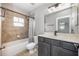 A cozy bathroom with a shower-tub combo, dark cabinets, and tiled walls at 124 Mcleods Way, Winter Springs, FL 32708