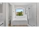 Elegant bathroom with a soaking tub, separate shower, and window for natural light at 12917 Grovehurst Ave, Winter Garden, FL 34787