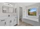 Bright bathroom featuring a soaking tub, modern vanity, and black hardware at 12917 Grovehurst Ave, Winter Garden, FL 34787