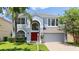 Charming two-story home features a red front door, arched entryway, and well-maintained landscaping at 12917 Grovehurst Ave, Winter Garden, FL 34787