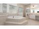 Bright bathroom with a large tub, glass block window, and tile surround at 1333 Killbricken Cir, Ormond Beach, FL 32174