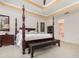 Comfortable bedroom features a four-poster bed, bench, stylish nightstand, and an ensuite bathroom at 1333 Killbricken Cir, Ormond Beach, FL 32174