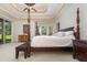Elegant bedroom with four-poster bed, bench, and natural light, showcasing serene decor and backyard view at 1333 Killbricken Cir, Ormond Beach, FL 32174