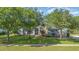 Single-story home with stone accents, beautiful trees, and a green lawn at 1333 Killbricken Cir, Ormond Beach, FL 32174
