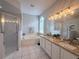 A main bathroom with dual vanities, granite countertops, a soaking tub, and a glass-enclosed shower at 14400 Saint Georges Hill Dr, Orlando, FL 32828