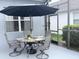 Outdoor dining on screened patio with an umbrella over the table and seating for four at 14400 Saint Georges Hill Dr, Orlando, FL 32828