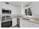Modern kitchen with stainless steel appliances, granite countertops, and white cabinetry at 1491 Granada Ave, Daytona Beach, FL 32117