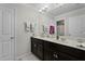Bathroom featuring double sink vanity, with dark cabinets, decorative orchid, and neutral countertops at 1553 Caterpillar St, St Cloud, FL 34771