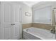 Clean white bathtub with tile surround and storage in the main bathroom at 1553 Caterpillar St, St Cloud, FL 34771