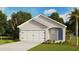 Charming single-Gathering home featuring a two-car garage, a blue front door, and lush landscaping at 171 Amberwood Way, Umatilla, FL 32784