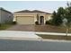 Charming single-story home featuring a two-car garage, brick driveway, and manicured landscaping at 176 Jensen Dr, Groveland, FL 34736