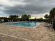 Community pool with brick patio, lounge chairs, and mature trees against a cloudy sky at 176 Jensen Dr, Groveland, FL 34736