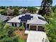 Aerial view of a modern home highlighting the roof covered in black solar panels, surrounded by green trees and lush landscaping at 1821 Windsor Dr, Winter Park, FL 32789
