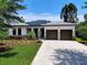 Attractive home showcasing solar panels, a spacious driveway, and a manicured lawn with tasteful landscaping at 1821 Windsor Dr, Winter Park, FL 32789