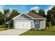 Charming single-story home with a white garage door, blue siding, and well-maintained landscaping at 210 Amberwood Way, Umatilla, FL 32784