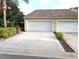View of the garage and long driveway of this tan house with manicured landscaping at 2299 Hawks Cove Cir, New Smyrna Beach, FL 32168