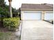 View of the garage and driveway of this tan house with manicured landscaping at 2299 Hawks Cove Cir, New Smyrna Beach, FL 32168