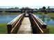 Picturesque walkway bridge with wooden railings leading to a gazebo on a sunny day over a pond at 2299 Hawks Cove Cir, New Smyrna Beach, FL 32168