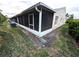 A view of the home's screened porch with white trim and a view of the exterior with partial grass and sky at 2299 Hawks Cove Cir, New Smyrna Beach, FL 32168