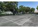 Community tennis court surrounded by trees and lush green vegetation on a sunny day at 2299 Hawks Cove Cir, New Smyrna Beach, FL 32168