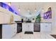 Bright kitchen features white cabinets, stainless steel appliances, and a unique, colorful accent wall and marbled tile floor at 2397 Albury Ave, Deltona, FL 32738