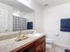 A well-lit bathroom showcasing a granite vanity, a sink, a toilet and patterned shower curtain at 3216 Casa Del Rey Ave, Kissimmee, FL 34746