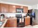 Well-lit kitchen featuring wood cabinets, granite countertops, and modern black appliances at 3216 Casa Del Rey Ave, Kissimmee, FL 34746