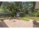 This backyard showcases a brick patio, fire pit, and a charming shed surrounded by lush greenery at 352 Inglenook Cir, Winter Springs, FL 32708