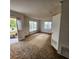 Spacious living room with three large windows, a side door and dated brown carpet at 4840 Judy Ann Ct, Orlando, FL 32808