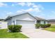 Attractive home exterior showcasing a two-car garage, a well-kept lawn, and mature landscaping for enhanced curb appeal at 520 Farmingham Ct, Oviedo, FL 32765