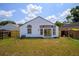 Backyard view of white house with sliding glass doors and black trim windows overlooking the yard at 6856 Ebans Bend, Orlando, FL 32807
