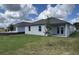 Backyard view showcasing a home with a lawn, trees, and a covered porch at 707 Junonia Blvd, New Smyrna Beach, FL 32168
