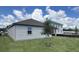 Backyard view featuring a new home with a tree in the lawn and construction in the background at 707 Junonia Blvd, New Smyrna Beach, FL 32168