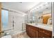 Well-lit bathroom featuring a glass door shower and wooden vanity with a large mirror and neutral ceramic tile at 134 Heron Bay Cir, Lake Mary, FL 32746