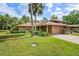 Charming home featuring a well-manicured lawn, lush landscaping, and mature palm trees in a tropical setting at 134 Heron Bay Cir, Lake Mary, FL 32746