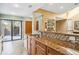 Bright kitchen features granite countertops, wood cabinets, tile backsplash, stainless steel sink, and access to the outdoor patio at 134 Heron Bay Cir, Lake Mary, FL 32746