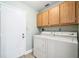 Laundry room featuring a white washer and dryer with light wood cabinets and a white door to the exterior at 134 Heron Bay Cir, Lake Mary, FL 32746