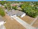 Aerial view of a single story home with a large driveway and mature trees in a residential neighborhood at 1340 Bakersfield Ave, Deltona, FL 32725