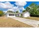 Charming one-story home with a long driveway, set against a backdrop of blue skies and lush trees at 1340 Bakersfield Ave, Deltona, FL 32725
