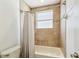 Cozy bathroom featuring neutral tile surround, white tub and shower combination, and a frosted glass window for natural light at 14003 Sobrado Dr, Orlando, FL 32837